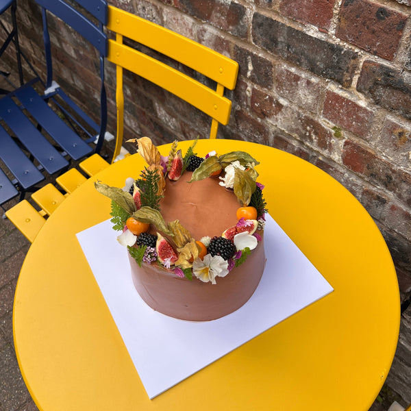 Fudgy chocolate birthday cake with dark chocolate buttercream, decorated with figs, blackberries, physalis and edible flower