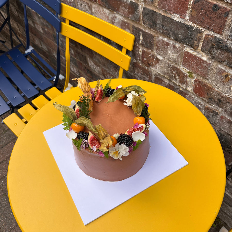 Fudgy chocolate birthday cake with dark chocolate buttercream, decorated with figs, blackberries, physalis and edible flower