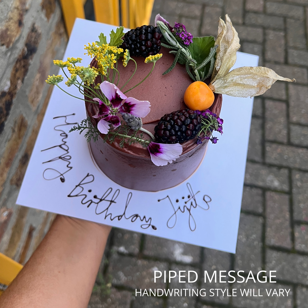 Fudgy double chocolate birthday cake with piped 'Happy Birthday' message, blackberries and edible flowers
