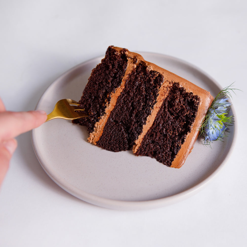 Slice of fudge double chocolate cake showing three layers of sponge and chocolate buttercream